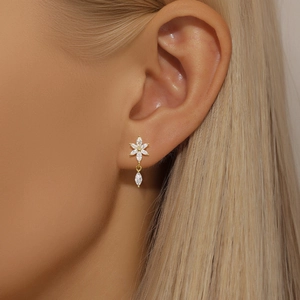 Close-up of golden petal stud earring with marquise-cut stones worn by a model
