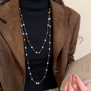 Detail der Vintage-Halskette mit Tigerauge und Perlen an Model mit Wildlederjacke