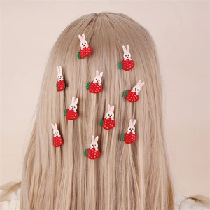 Detailed view of embroidered strawberry and bunny hair clips on blonde hair for girls