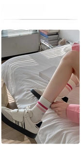 Close-up of white striped cotton socks with pink stripes and casual sneakers in soft light