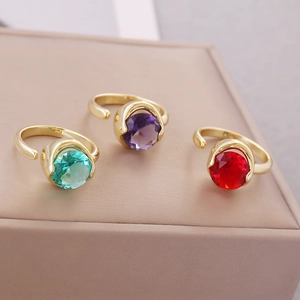 Detailed view of red, green, and purple cubic zirconia rings on a soft jewelry box
