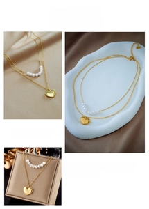 Detail of double-layer gold necklace with white pearls and a heart pendant on silk