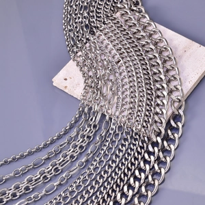 Silver stainless steel Cuban and Figaro link chains displayed on a grey stone pedestal