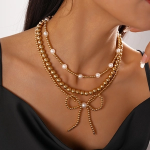 Detail of a 3-layer gold beaded necklace with pearls and a woven bow pendant
