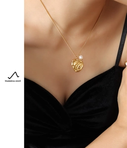 Close-up of golden irregular hammered pendant necklace with pearl on a stainless steel chain
