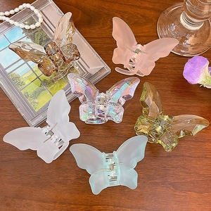 Set of 6 colorful crystal butterfly hair claws in various finishes on a wooden table