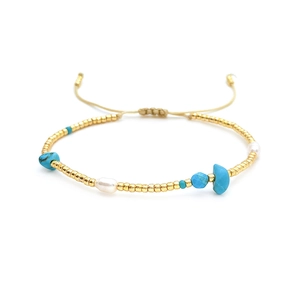 Detail of bohemian handmade gold bead bracelet with turquoise and freshwater pearl accents