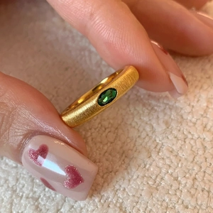 Vintage French brushed gold ring featuring an oval emerald green gemstone on finger