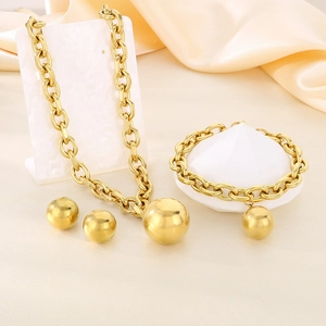 Macro detail of chunky gold chain jewelry set with large spherical pendants on silk