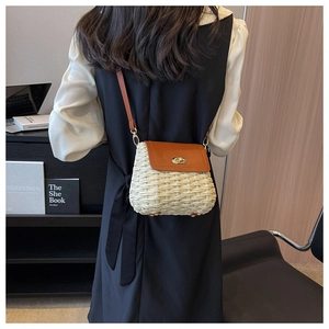 Detail of crossbody straw bag in cream with brown leather flap and gold lock detail