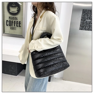 Fashionable black quilted puffer tote bag shown on a model in an urban lifestyle setting