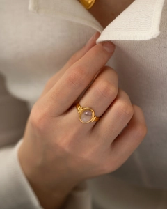 Detailed view of a gold oval pink gemstone open ring on model's hand with knitwear