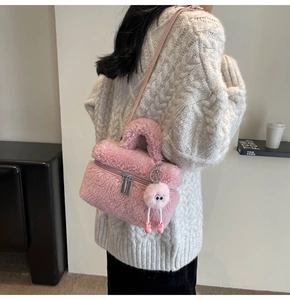 Detail of pink plush bucket bag with matching fuzzy charm shown in a cozy home setting