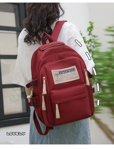 Close-up of waterproof burgundy nylon backpack with multi-pocket design and side buckles