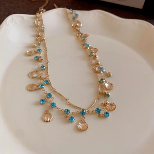 Elegant gold double-layered butterfly necklace with blue crystals on a white ceramic plate