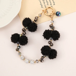 Detail of beaded phone strap with black fluffy pompom, gray crystal beads and gold clasp