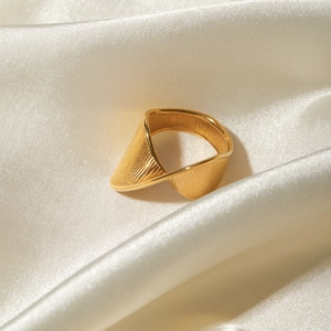 Detailed macro of the 18k gold plated stainless steel twisted ring on silk fabric