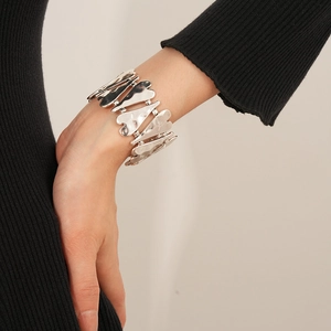Détail d'un bracelet en métal argenté en forme de cœur porté sur un fond beige neutre