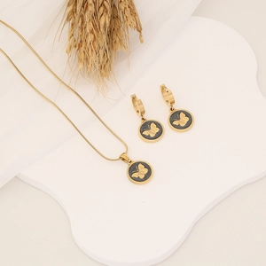 Golden butterfly pendant necklace and earrings set on a white ceramic tray decoration