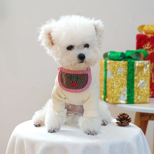 Detail of a beige knit pet sweater with a reindeer bib, styled in a festive scene