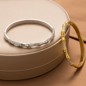 Bamboo style gold and silver bangles with micro-pave zircons on a beige display stand