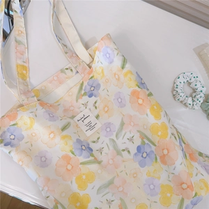 Detailed close-up of the colorful floral print and fabric label on a white cotton tote bag