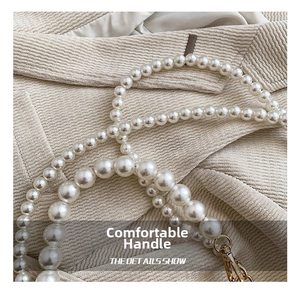 Détails de la bandoulière en perles blanches avec fermoirs en métal doré sur beige