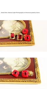 Macro detail of red vintage enamel earrings with square zircon and gold wavy texture