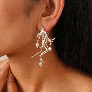 Detail of silver twisted irregular earrings with faux pearls worn by a female model