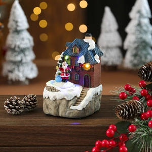 Dettaglio villaggio di Natale luminoso con casa innevata in resina e Babbo Natale