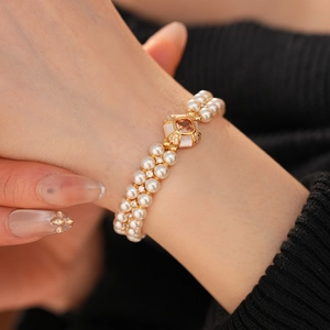 Détail d'un bracelet double rang de perles avec boucle dorée sertie de pierres champagne
