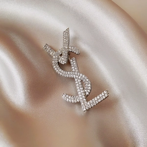 Macro detail of silver brooch with crystals on champagne silk background