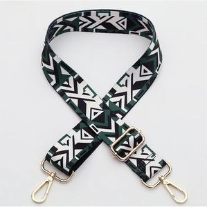 Detail of woven adjustable wide bag strap with ethnic geometric patterns and gold metal clips