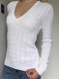 Gros plan d'un pull en maille blanc à col en V avec une texture détaillée en maille torsadée