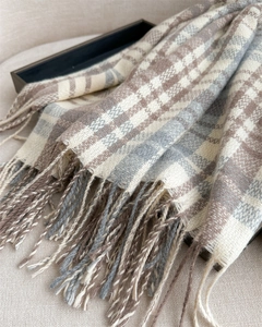 Detail of classic plaid pattern and fringe tassels on a warm cashmere-feel winter scarf