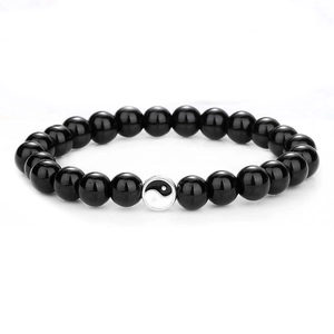 Detailaufnahme des elastischen Perlenarmbands mit schwarzen Kugeln und weißer Tai Chi Perle