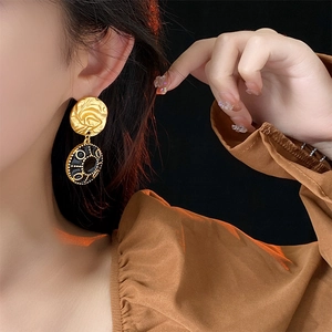 Close-up of vintage gold earrings with black enamel geometric charms and gemstone detailing