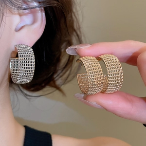 Detailed view of golden mesh-textured C-shaped hoop earrings with intricate metal weaving