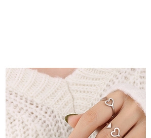 Detail of silver U-shaped heart and triangle rings worn on a hand with knit background