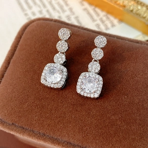 Macro shot of square zircon earrings on velvet box with elegant silver needles