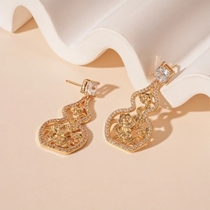 Macro detail of gold gourd earrings with hollow rose patterns and sparkling zircons