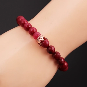 Detail of 8mm red beaded bracelet featuring a rose gold crown charm with white zircons