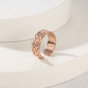 Dettaglio anello a maglia intrecciata oro rosa su piedistallo circolare bianco