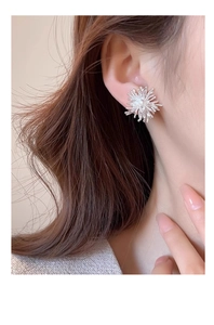 Detailed close-up of a silver zircon firework earring on a female model's ear