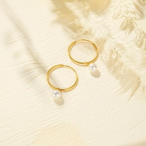 Detailed view of elegant gold hoop earrings featuring polished white pearl pendants