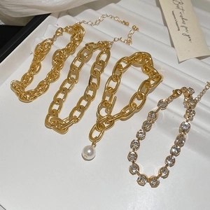 Detailed shot of four gold-tone metal chain bracelets with pearls and rhinestones