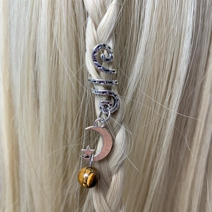 Detail of silver spiral hair jewelry with moon, star charms and tiger eye bead on braids