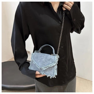 Detail of light blue denim mini bag with fringed edges and silver chain strap