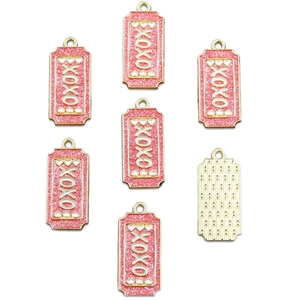 Detail of pink glitter enamel XOXO pendants with gold metal border and textured back side