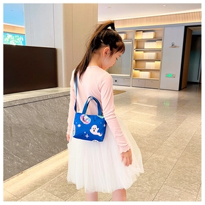 Blue mini tote bag with cartoon ghosts and stars worn by a young girl in a hotel lobby